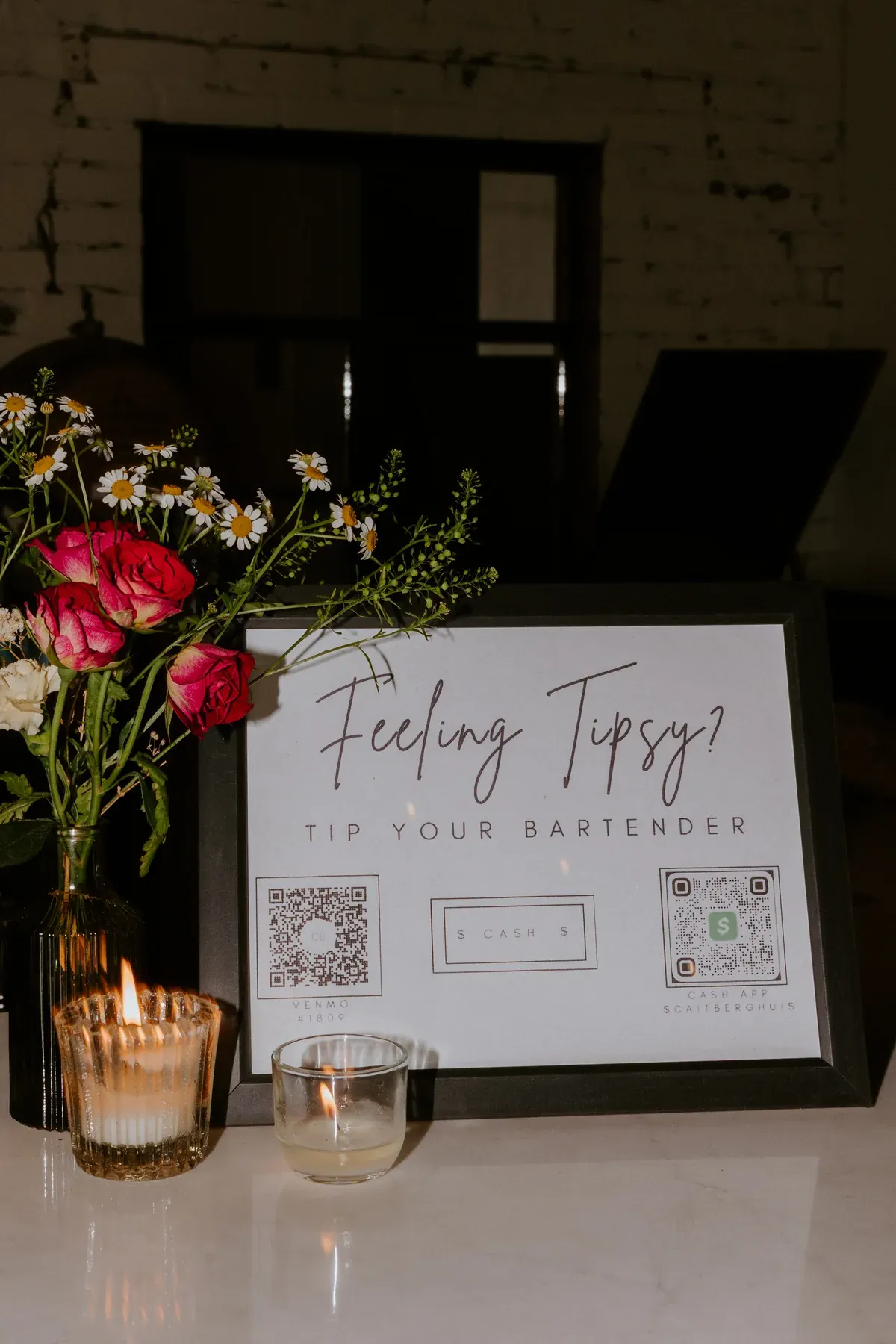 A Tip Your Bartender sign beside red roses on the bar at a downtown Indianapolis engagement party venue