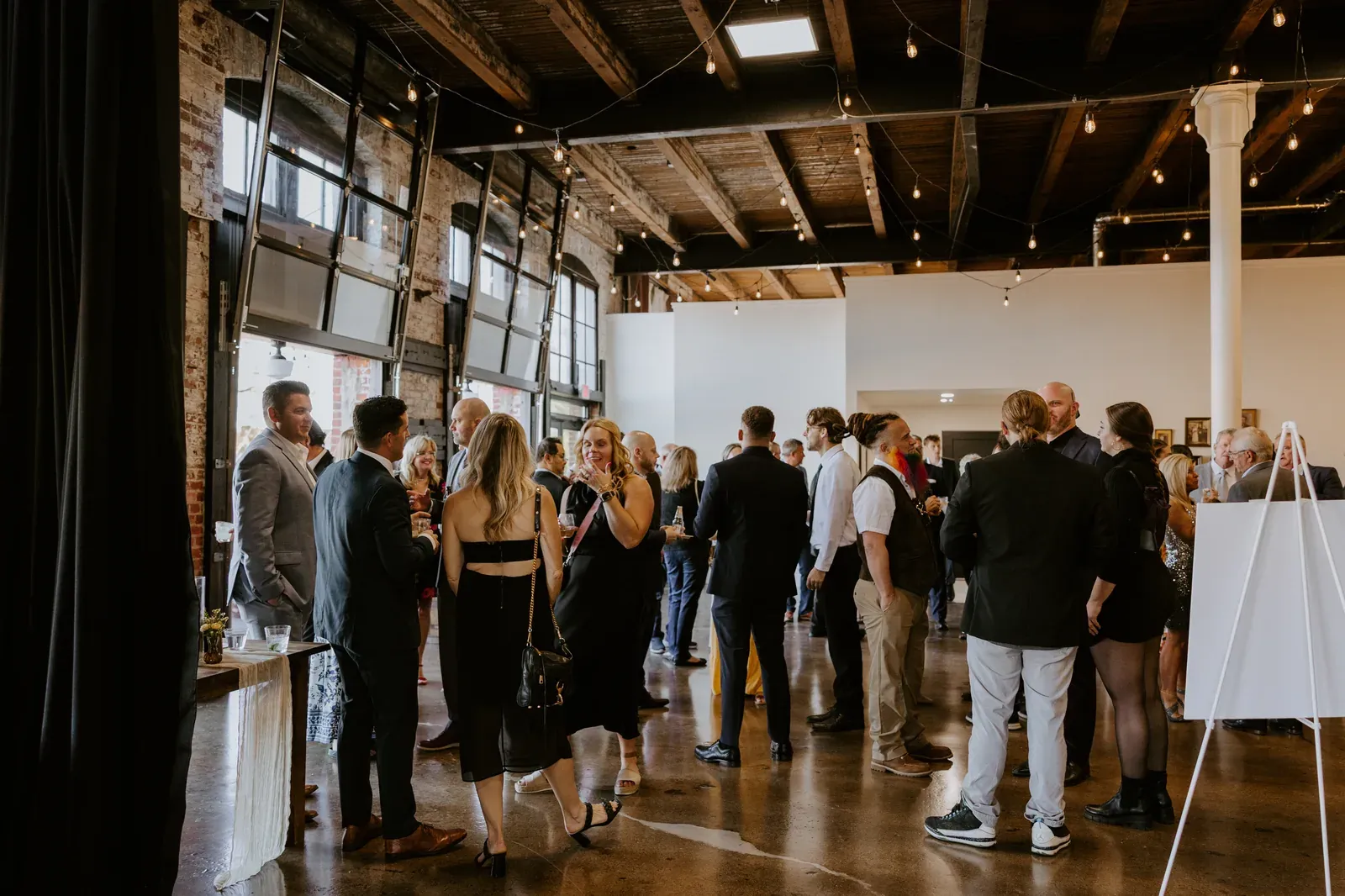 Guests mingling with drinks under warm string lights at a downtown Indianapolis engagement party