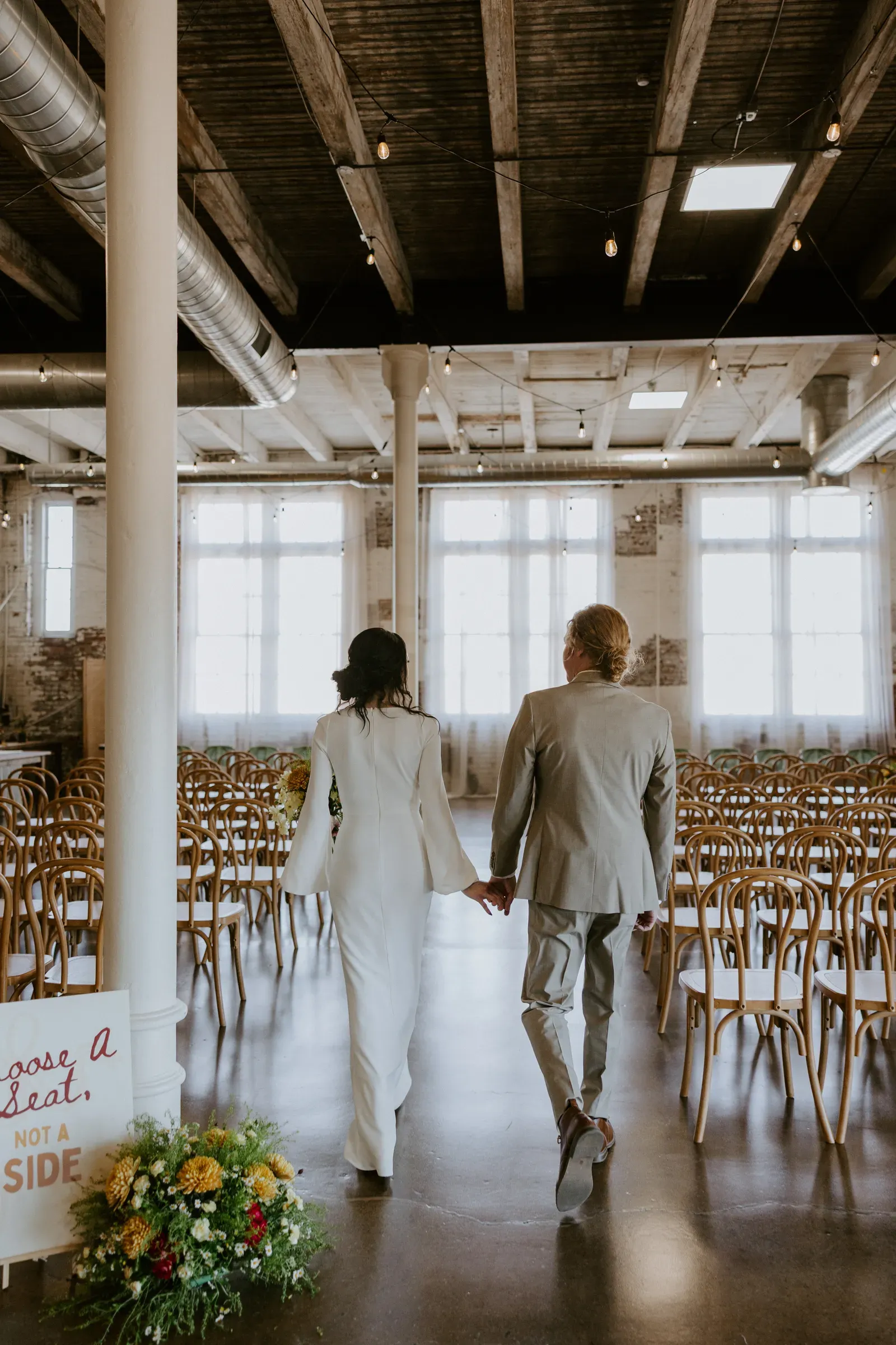 Indianapolis wedding ceremony in the full Edison Room at 24 Shelby with guests seated, ceremony aisle, original wood-beam ceilings, and oversized windows