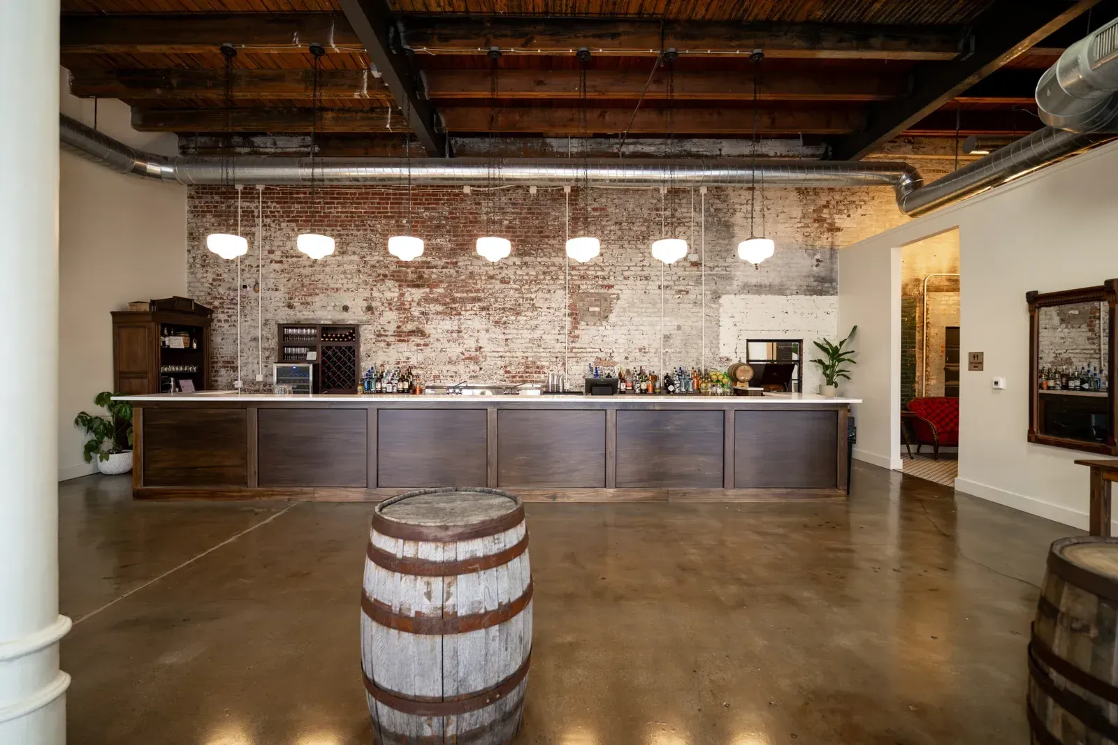 The fully stocked Libations Lounge bar at 24 Shelby with a whiskey barrel out front, where the in-house bartenders run cocktail-making classes for holiday parties