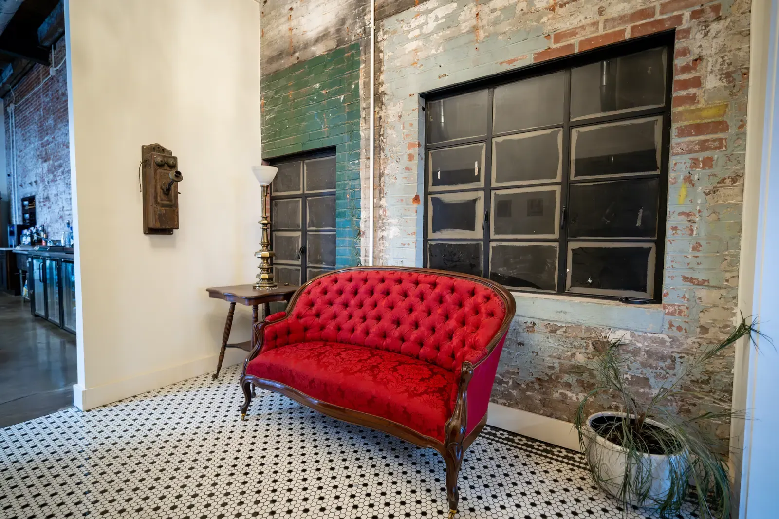 Lounge seating with a red velvet vintage sofa against exposed brick in a downtown Indianapolis venue