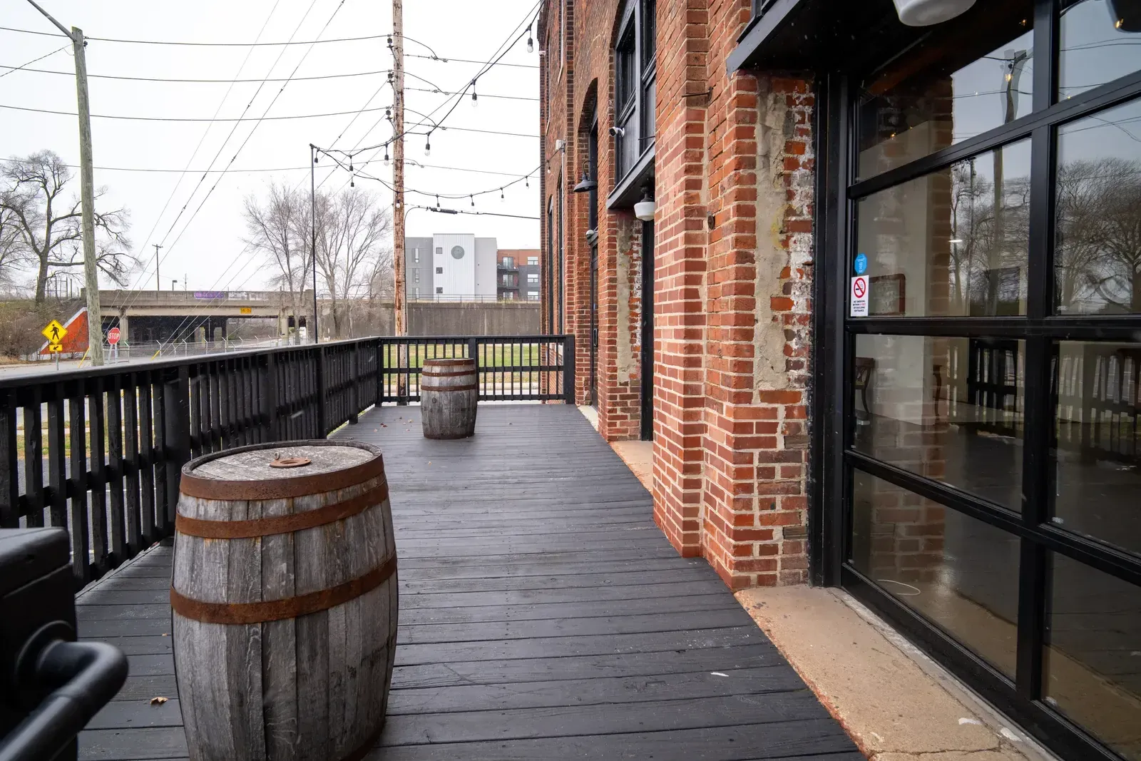 The Prohibition Patio at 24 Shelby with whiskey barrels and string lights against the 1898 brick, the cocktail hour space at this downtown Indianapolis wedding venue.