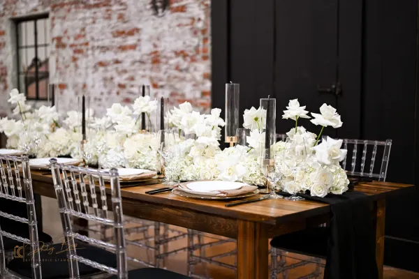 Farm tables and ghost chairs set up at 24 Shelby under Edison string lights, an example of furniture included with a venue rental at the venue-plus-services tier.